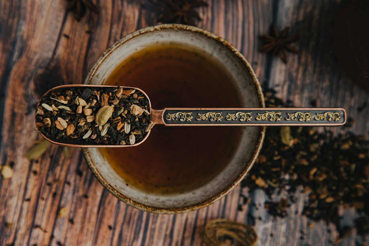 Löffel mit Gewürzen und Tasse Chai